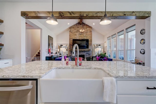 kitchen with sink, a brick fireplace, vaulted ceiling with beams, stainless steel dishwasher, and pendant lighting