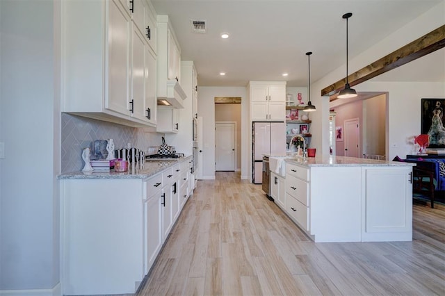 kitchen featuring white cabinets, pendant lighting, decorative backsplash, and an island with sink