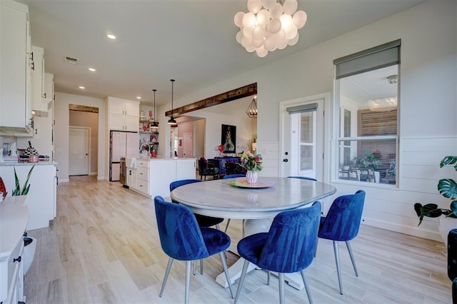 dining space featuring light wood-type flooring and a notable chandelier