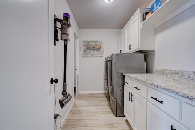 washroom with cabinets, light hardwood / wood-style flooring, and washing machine and clothes dryer