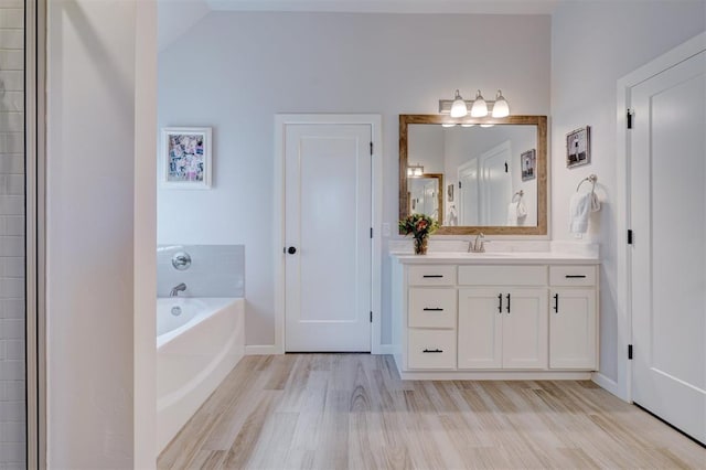 bathroom featuring hardwood / wood-style flooring, vanity, and a tub to relax in