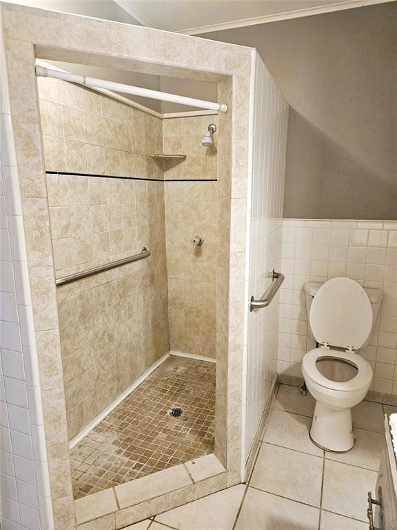 bathroom featuring tile patterned flooring, toilet, a tile shower, and tile walls