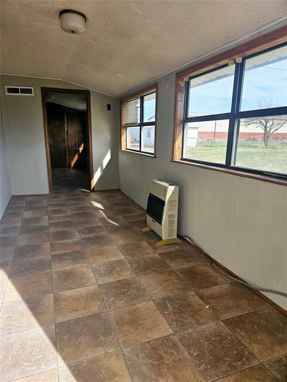 spare room with heating unit, a wealth of natural light, and a textured ceiling