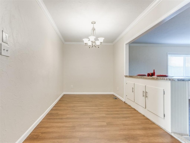 unfurnished dining area with a chandelier, ornamental molding, and light wood-type flooring