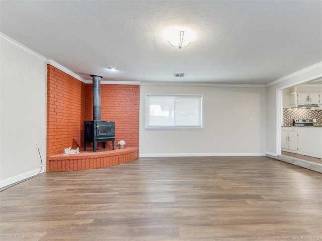 unfurnished living room featuring a wood stove, crown molding, and light hardwood / wood-style flooring