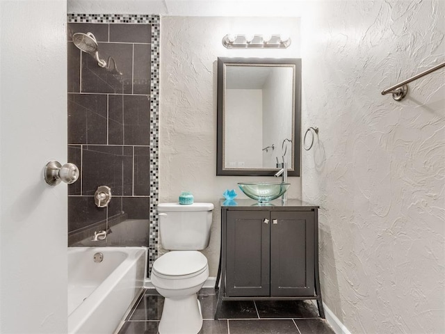 full bathroom with tile patterned flooring, vanity, tiled shower / bath combo, and toilet