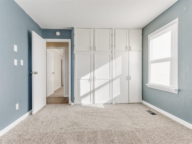 unfurnished bedroom with multiple windows, a closet, and light colored carpet