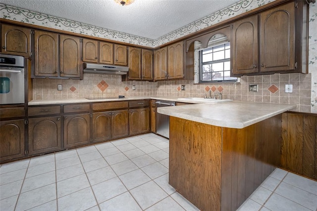 kitchen with kitchen peninsula, appliances with stainless steel finishes, a textured ceiling, sink, and light tile patterned flooring