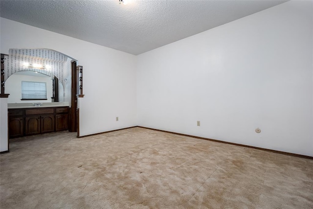 unfurnished bedroom featuring light carpet, sink, and a textured ceiling