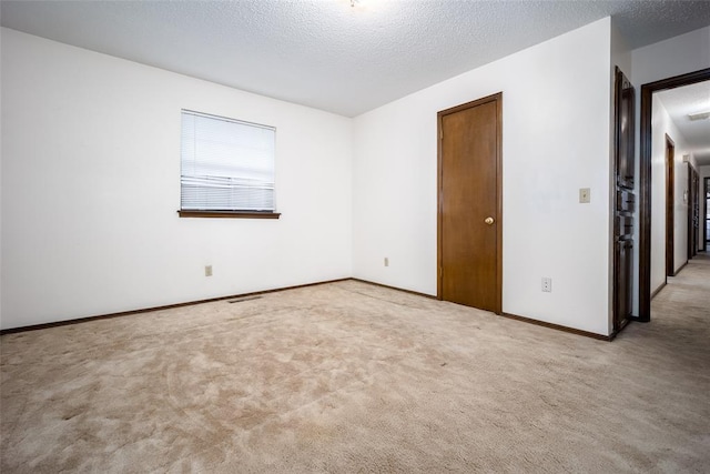 carpeted empty room with a textured ceiling