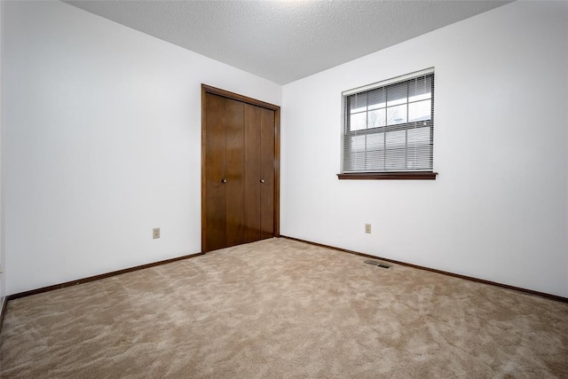 unfurnished bedroom with carpet floors, a textured ceiling, and a closet