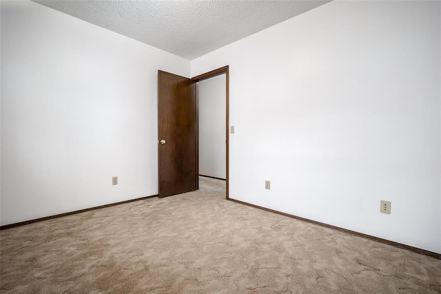 empty room with light colored carpet and a textured ceiling