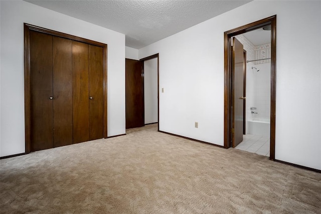 unfurnished bedroom with connected bathroom, light carpet, and a textured ceiling