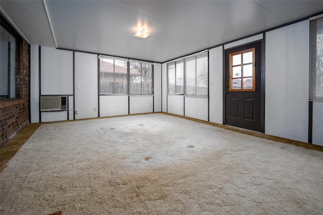 carpeted empty room featuring brick wall