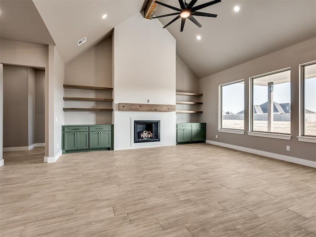 unfurnished living room with beamed ceiling, ceiling fan, light wood-type flooring, and high vaulted ceiling