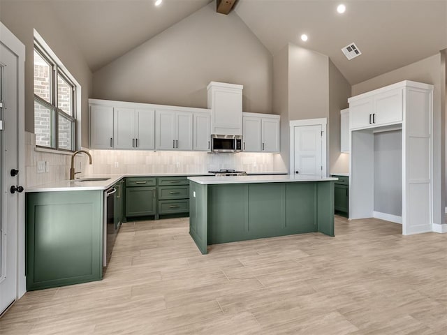 kitchen featuring high vaulted ceiling, green cabinets, sink, beamed ceiling, and stainless steel appliances