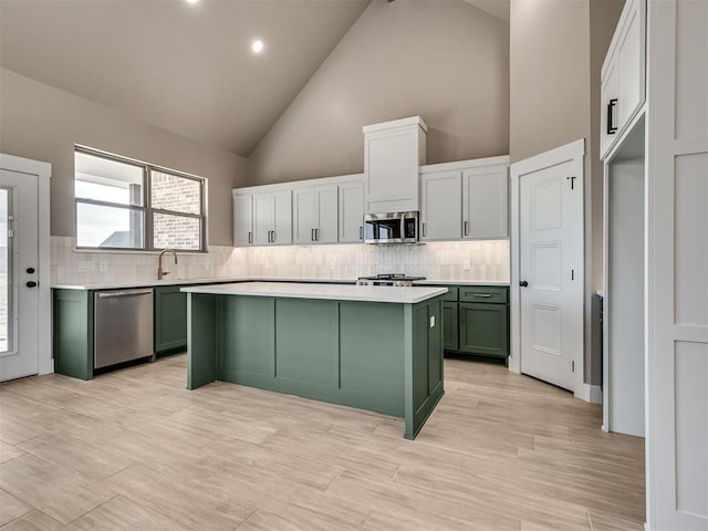 kitchen featuring appliances with stainless steel finishes, backsplash, high vaulted ceiling, white cabinets, and green cabinets