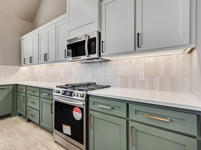 kitchen featuring tasteful backsplash, white cabinets, stainless steel appliances, and lofted ceiling