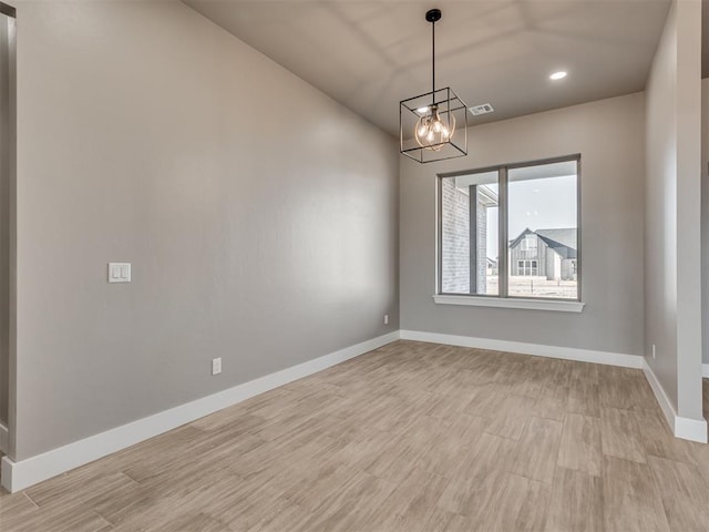 unfurnished room with light wood-type flooring and a chandelier