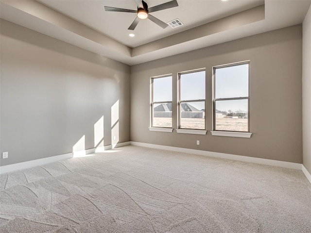 unfurnished room with light carpet, a tray ceiling, and ceiling fan