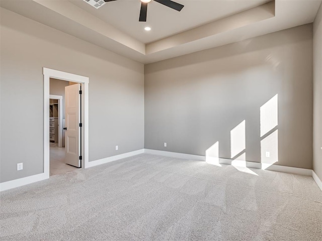 carpeted spare room with ceiling fan and a raised ceiling