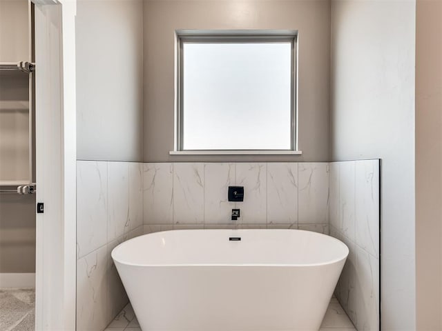 bathroom featuring a bath and tile walls