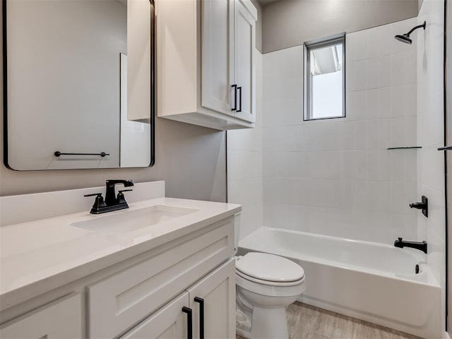 full bathroom with hardwood / wood-style floors, vanity, toilet, and tiled shower / bath