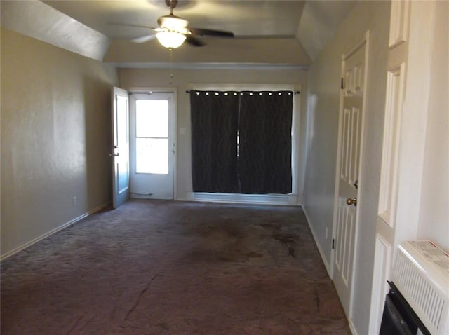 spare room with dark colored carpet, heating unit, and vaulted ceiling