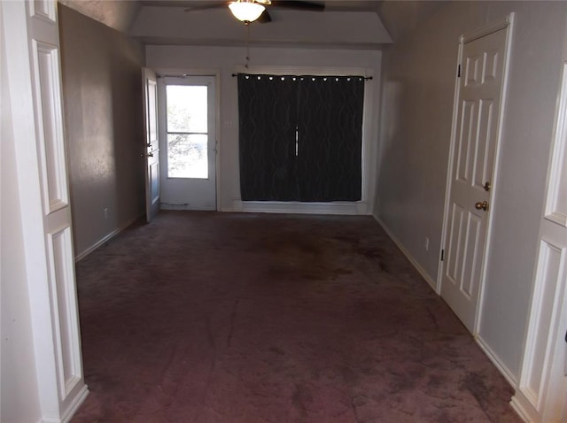 spare room featuring ceiling fan, dark carpet, and vaulted ceiling