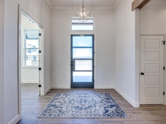 entrance foyer featuring a chandelier, light wood-type flooring, and crown molding