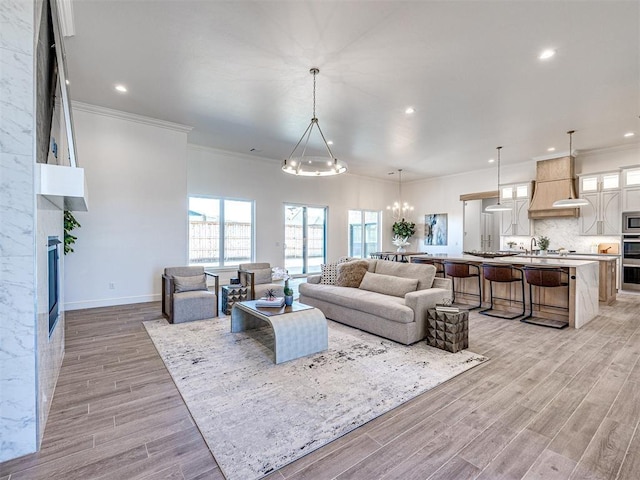 living room featuring a notable chandelier, ornamental molding, and light hardwood / wood-style flooring