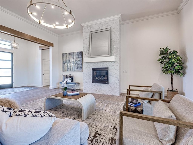 living room with a chandelier, a fireplace, wood-type flooring, and ornamental molding