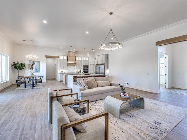 living room with an inviting chandelier, ornamental molding, and light hardwood / wood-style flooring