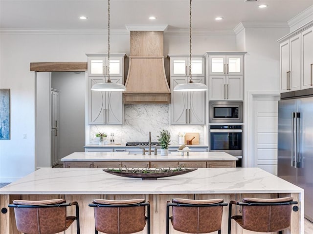 kitchen featuring light stone counters, an island with sink, appliances with stainless steel finishes, and tasteful backsplash