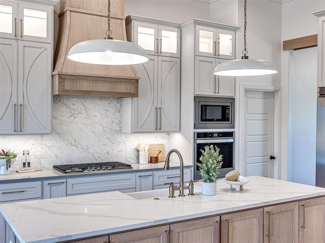 kitchen featuring light brown cabinetry, decorative backsplash, hanging light fixtures, and stainless steel appliances