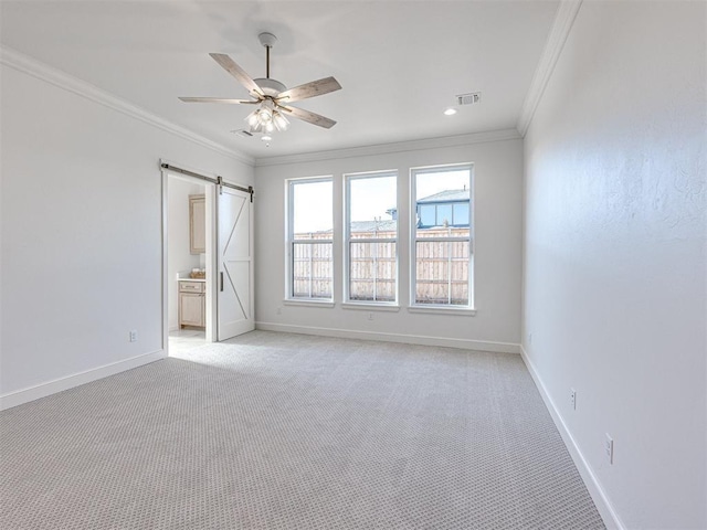 unfurnished room with ceiling fan, a barn door, ornamental molding, and light carpet