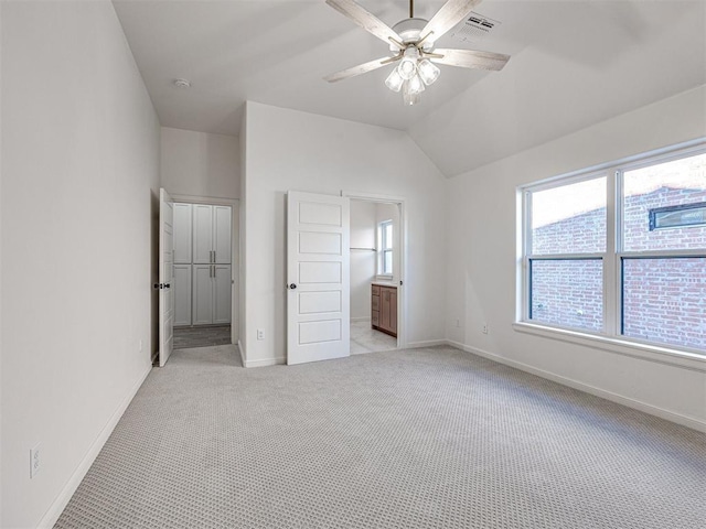 unfurnished bedroom with ceiling fan, light colored carpet, lofted ceiling, and ensuite bathroom