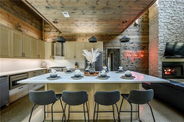 kitchen featuring a center island, wooden ceiling, a stone fireplace, wooden walls, and wall chimney exhaust hood