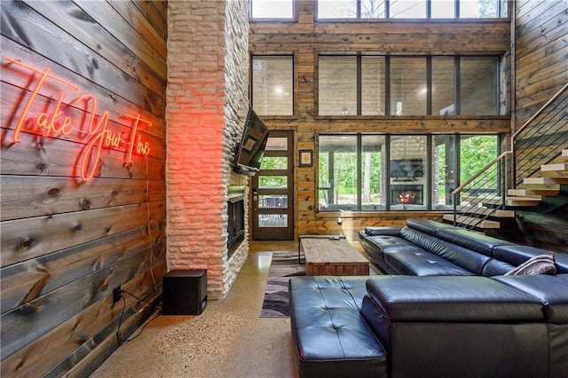 unfurnished living room featuring a fireplace, wooden walls, and a high ceiling