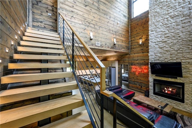 stairway featuring an outdoor stone fireplace and a high ceiling