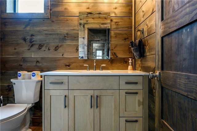 bathroom featuring wood walls, vanity, and toilet