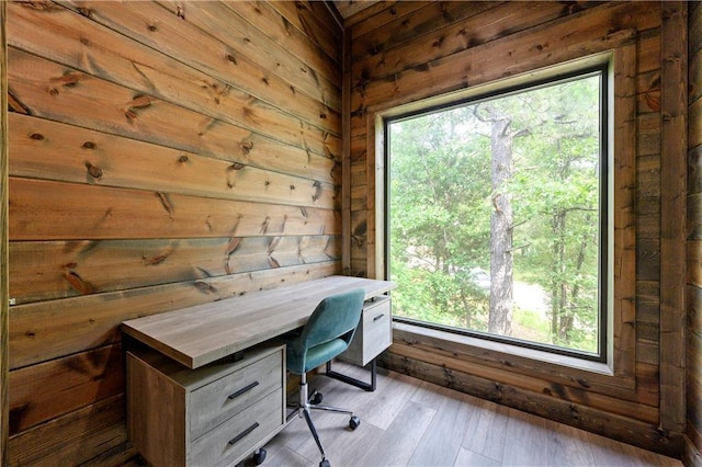 unfurnished office with a healthy amount of sunlight, light hardwood / wood-style floors, and wood walls