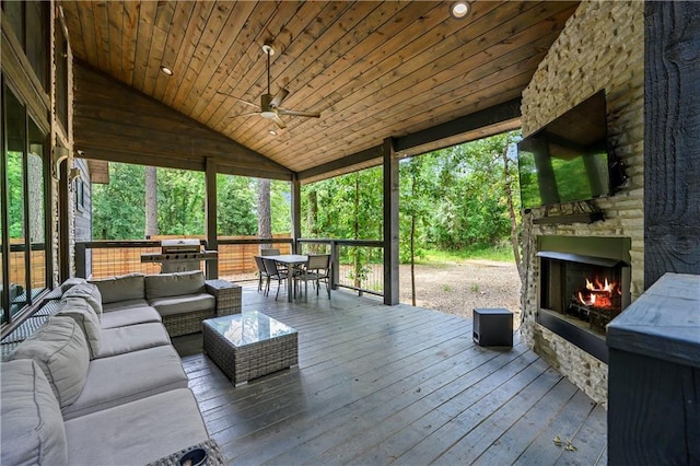 wooden deck featuring an outdoor living space with a fireplace, ceiling fan, and area for grilling