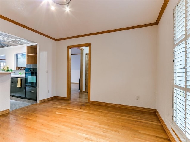 spare room featuring crown molding and light wood-type flooring