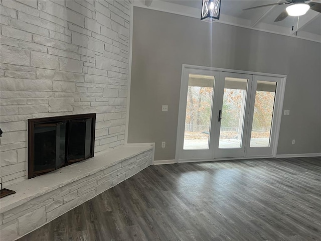 unfurnished living room featuring ceiling fan, a stone fireplace, ornamental molding, and dark wood-type flooring