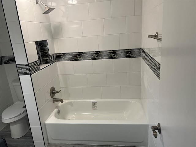 bathroom with tiled shower / bath combo and toilet