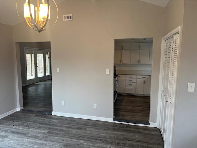 empty room with dark wood-type flooring and a chandelier