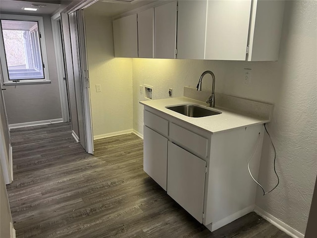 kitchen with dark hardwood / wood-style flooring, white cabinetry, and sink