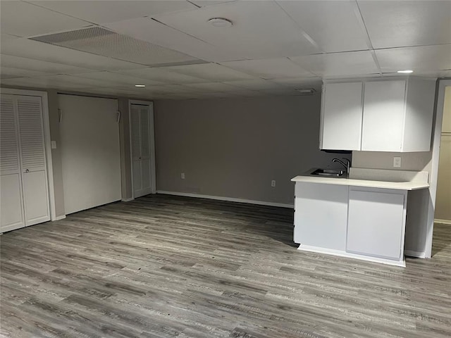 kitchen with white cabinets, a paneled ceiling, light hardwood / wood-style floors, and sink