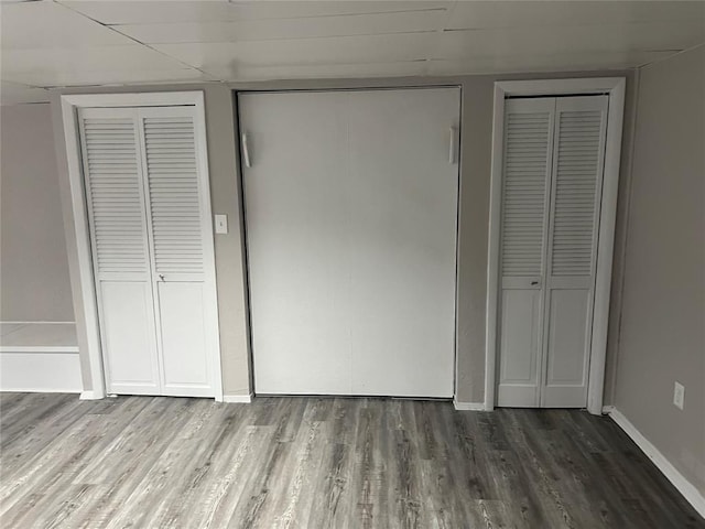 unfurnished bedroom with multiple closets and hardwood / wood-style floors